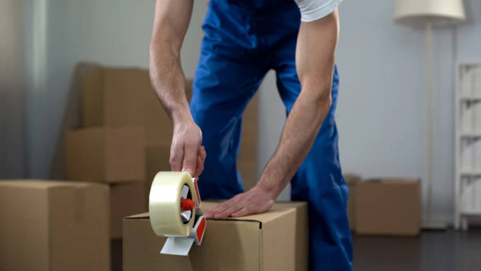 Moving staff packing a moving box and putting packaging tape