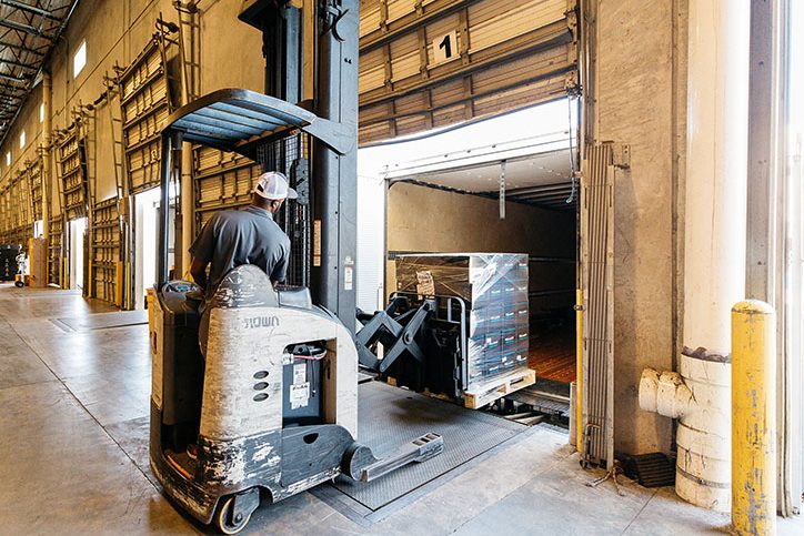 Forklift operator moving pallet of boxes