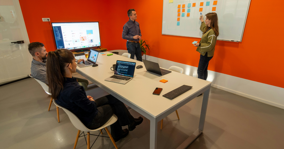 Two corporate professionals with a white board and sticker chart in a conference room after a recent office move.