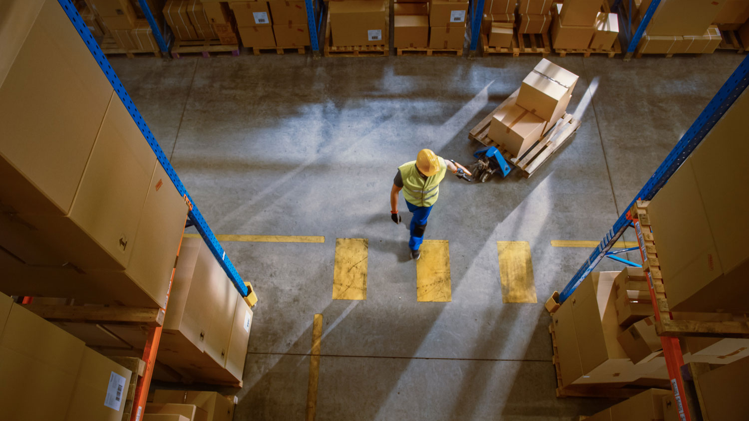 Construction worker pulling moving boxes on wooden cart from aerial view