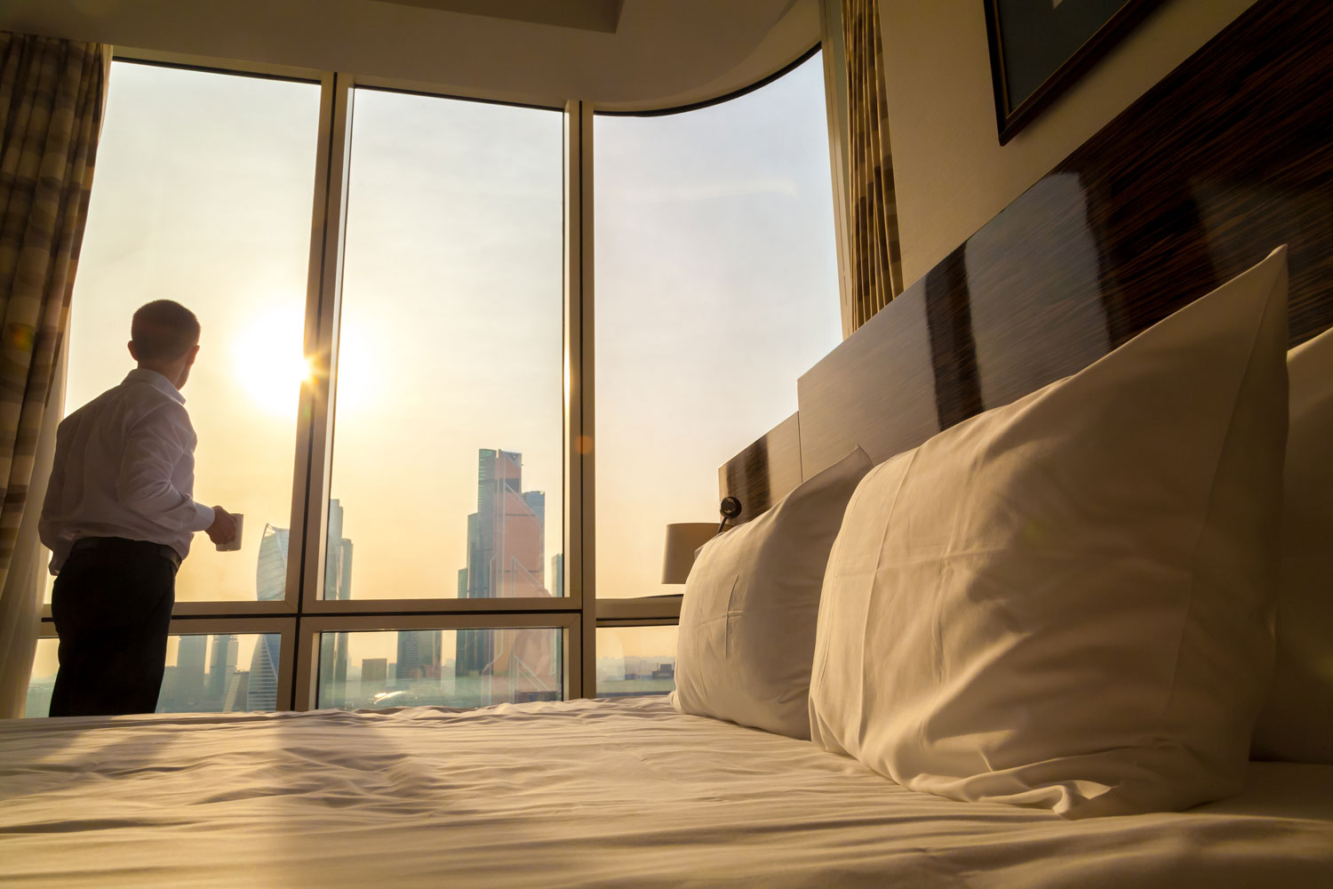 man looking out hotel window